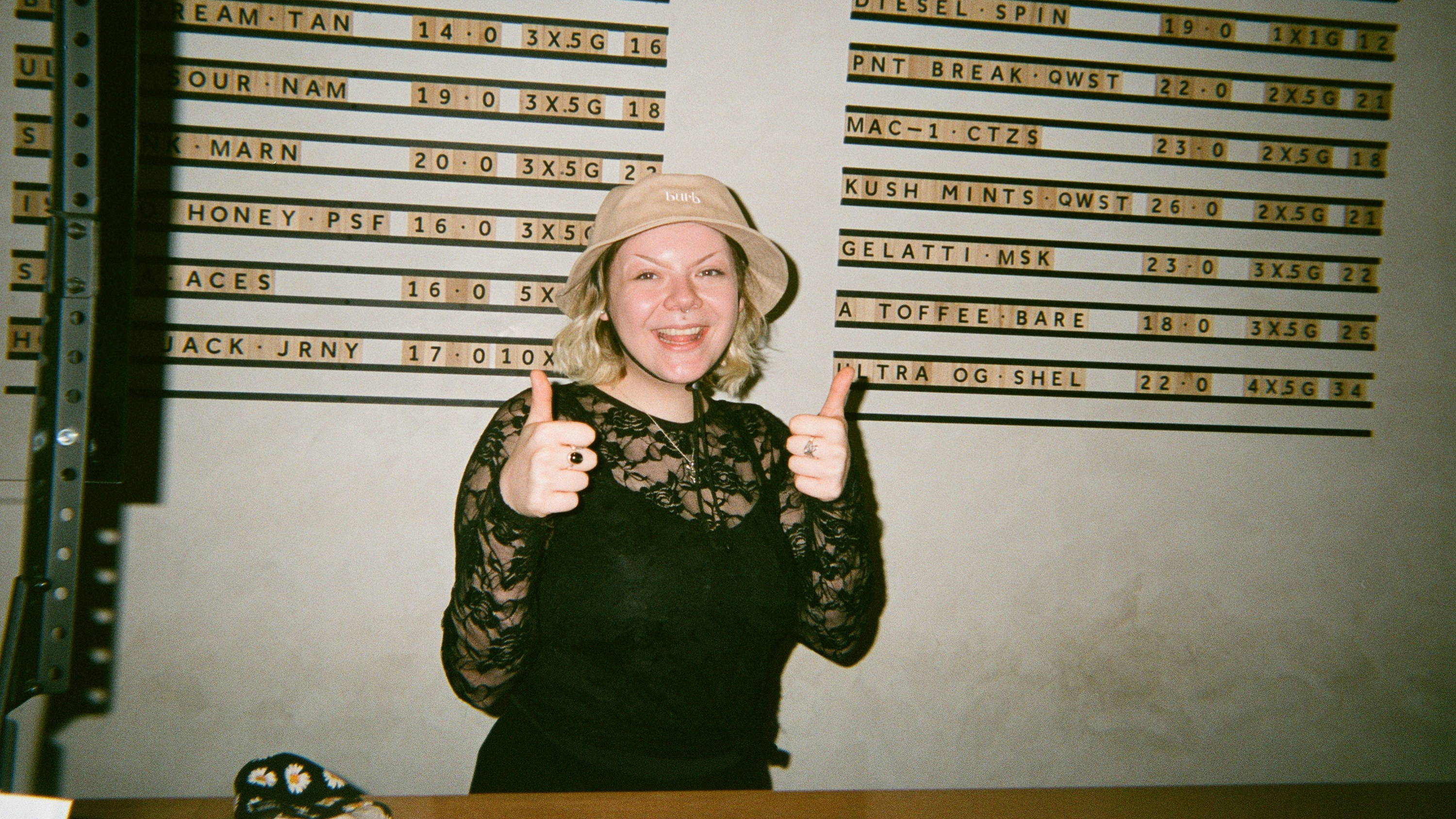 A photo of our burbtender giving a thumbs up in front of our Burb cannabis menu.