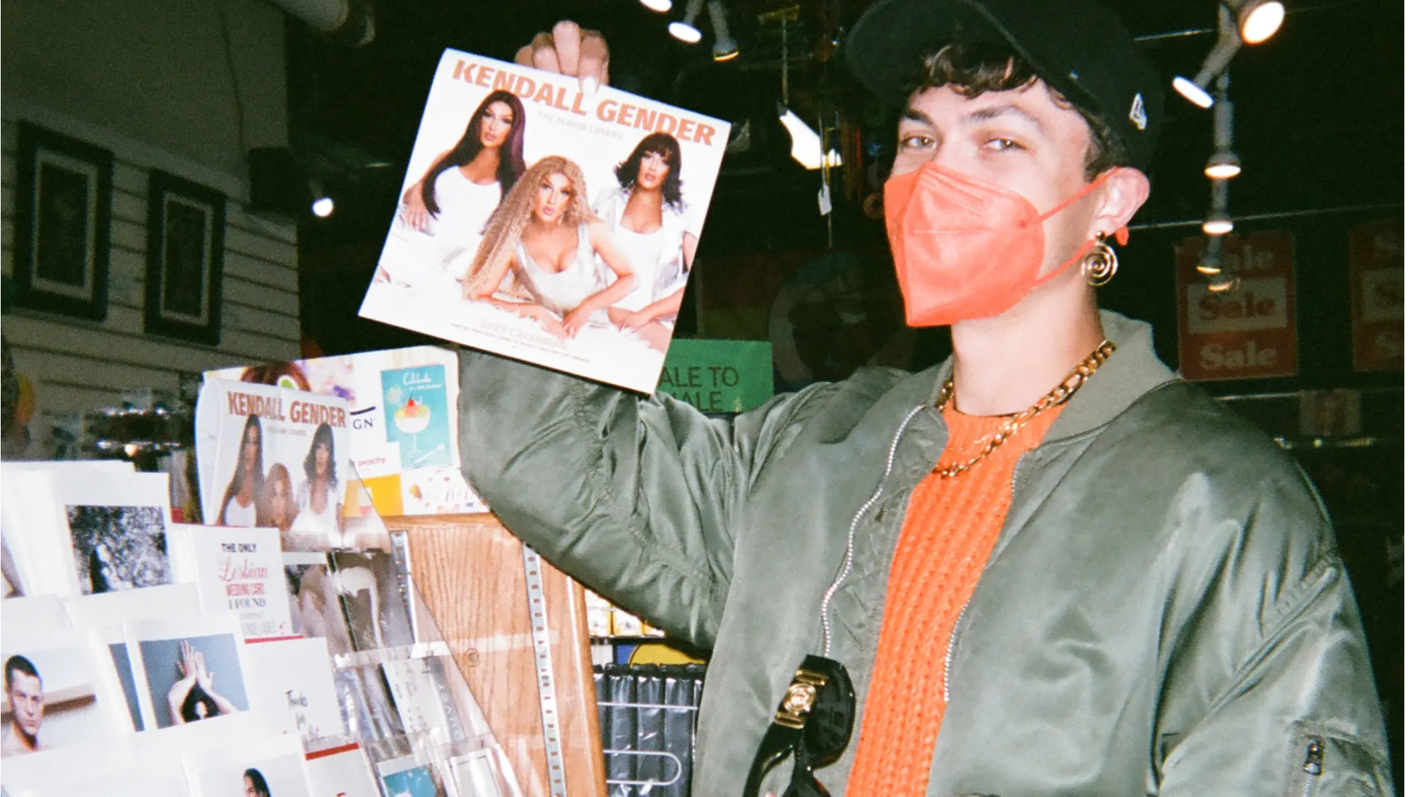 A photo of Venus wearing a mask in Little Sister's Book and Art Emporium, holding a calendar.