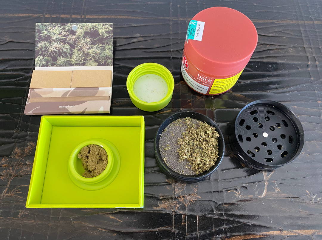 A photo of dried flower, kief, rollies on top of a table.