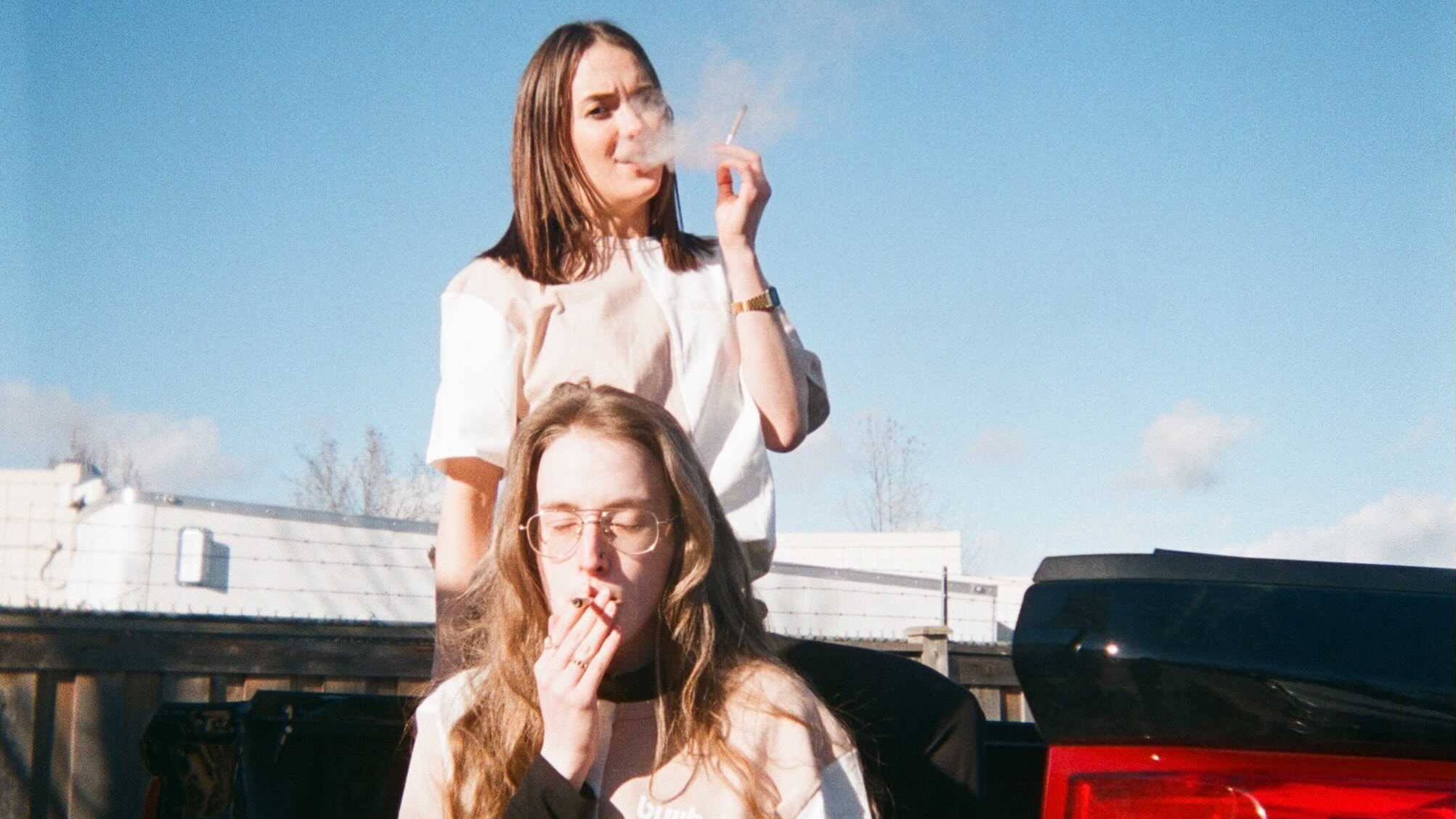 A photo of two of our team members smoking cannabis outside on a pickup truck.